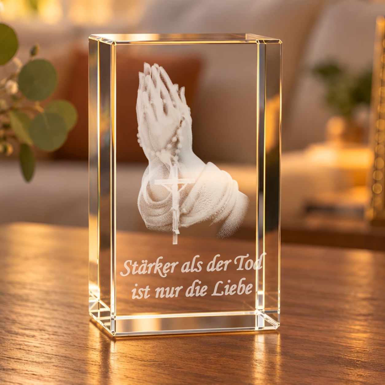 Glaskristall Betende Hände mit Rosenkranz und Spruch, 3D-Laserinnengravur, auf einem Holztisch im Wohnzimmer bei warmem Licht
