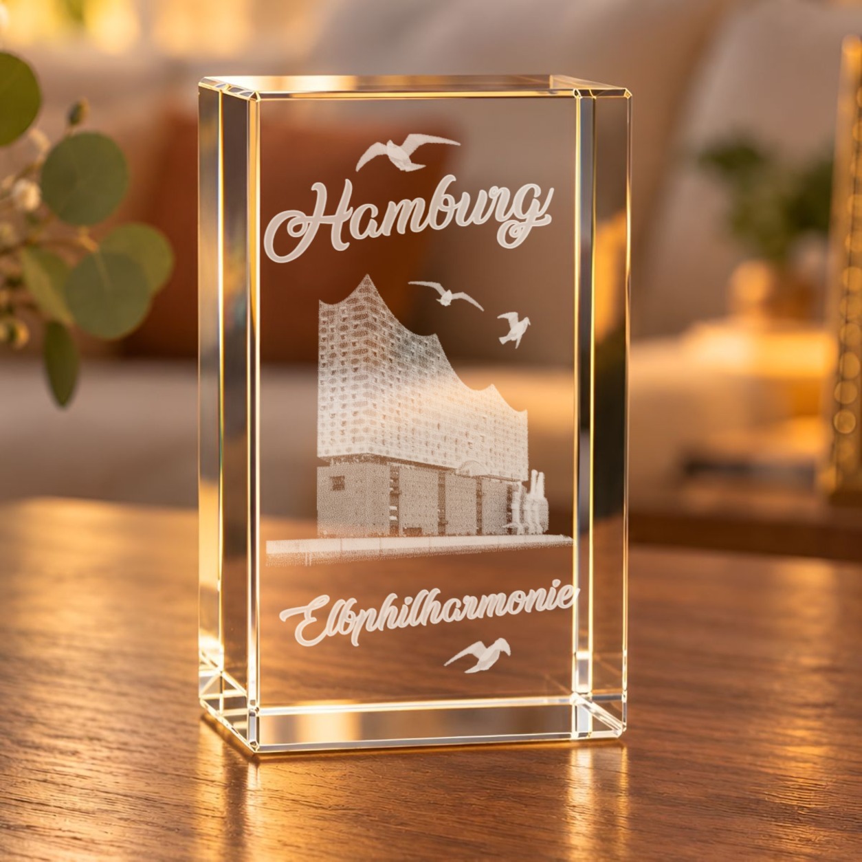 Glaskristall Elbphilharmonie mit 3D-Innengravur, Möwen und Schriftzug „Hamburg“ auf einem Holztisch im Wohnraum
