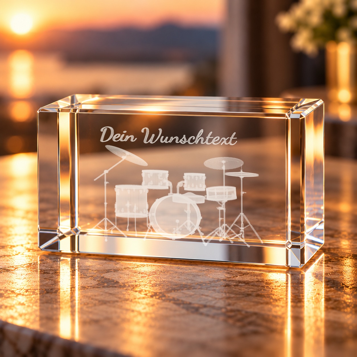 Glaskristall Schlagzeug mit Wunschtext: 3D-Laserinnengravur eines Drumsets im Glasquader auf einer Ablage im Wohnraum bei Abendlicht