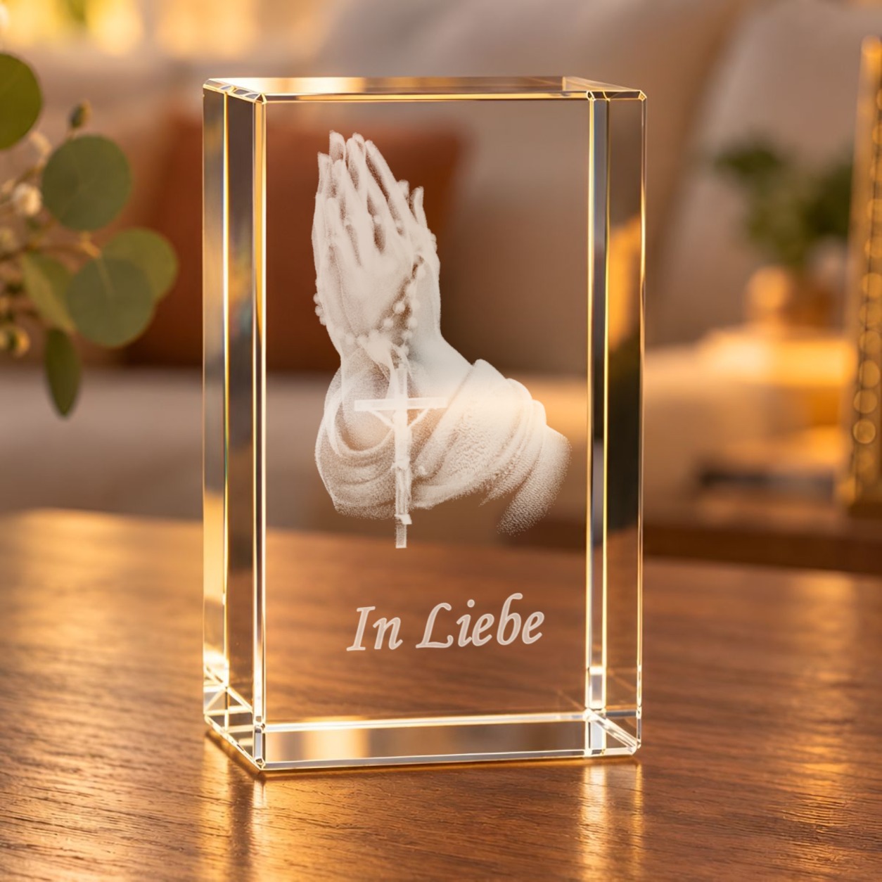 Glaskristall Betende Hände mit Rosenkranz und Schriftzug „In Liebe“ auf einem Holztisch im warm beleuchteten Wohnzimmer