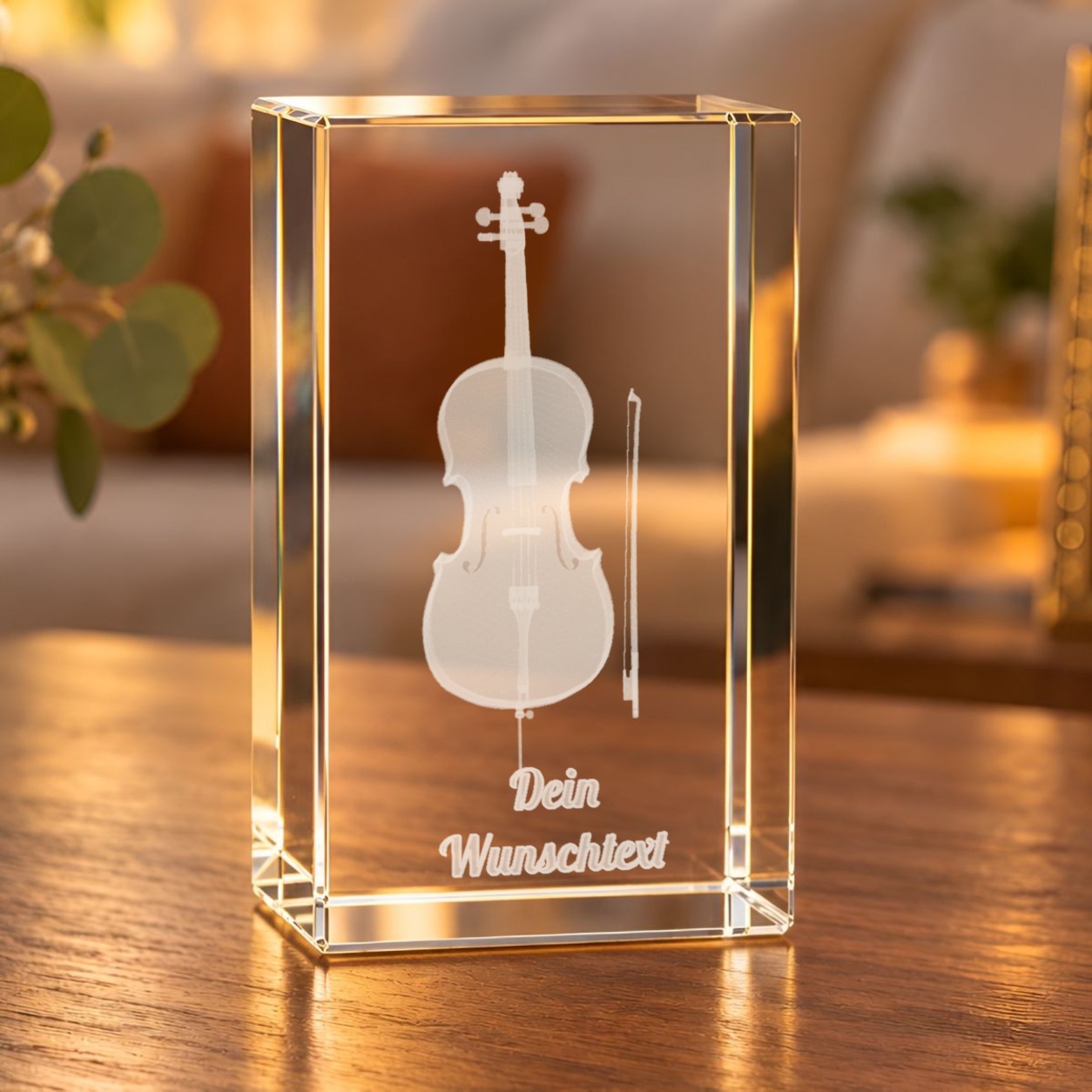 Glaskristall Cello mit Wunschtext: Glasquader mit 3D-Gravur eines Cellos samt Bogen auf einem Holztisch im Wohnraum