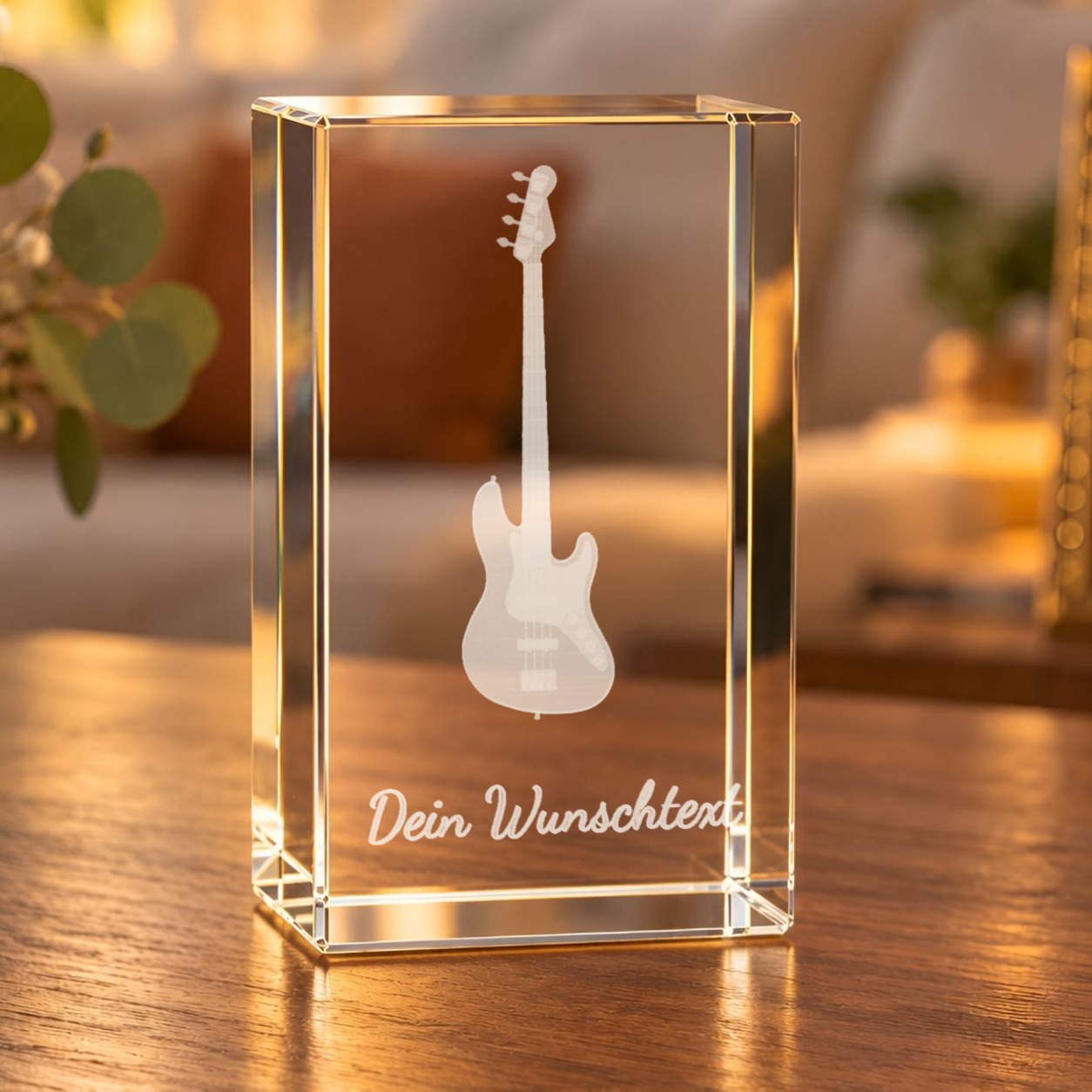 Glaskristall Bassgitarre mit Wunschtext: Quader aus Kristallglas mit gravierter Bassgitarre auf einem Holztisch im Wohnzimmer