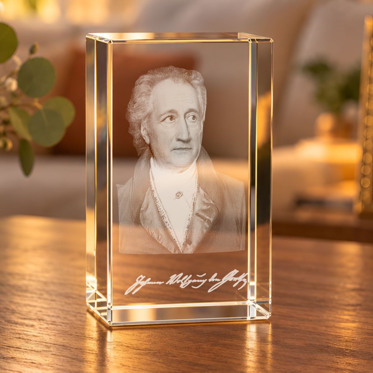 Glaskristall Goethe mit 3D-Innengravur: Porträt und Schriftzug im Glasquader auf einem Holztisch im Wohnzimmer