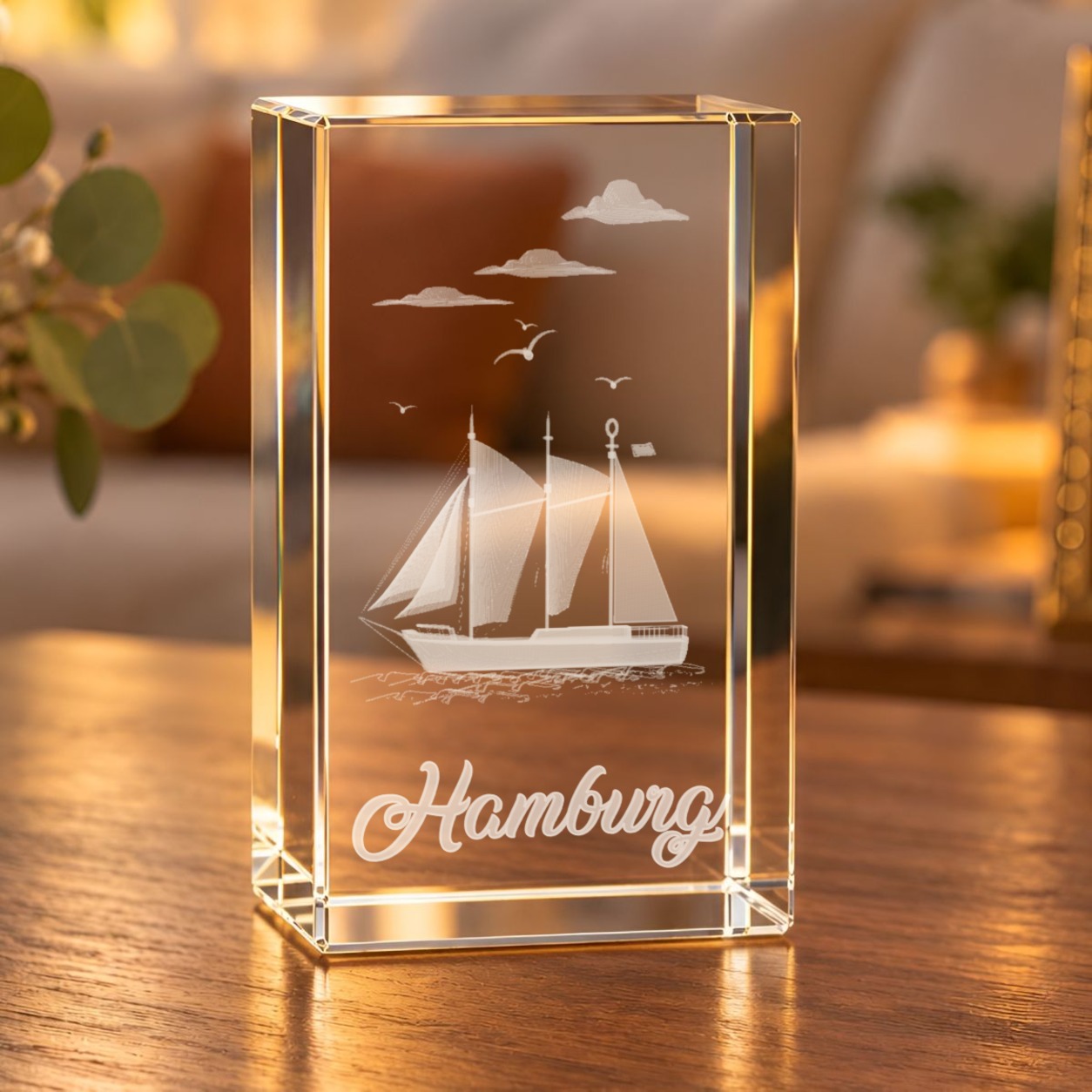 3D-Glaskristall Hamburg mit Segelschiff, Möwen und Schriftzug „Hamburg“ auf einem Holztisch im Wohnzimmer