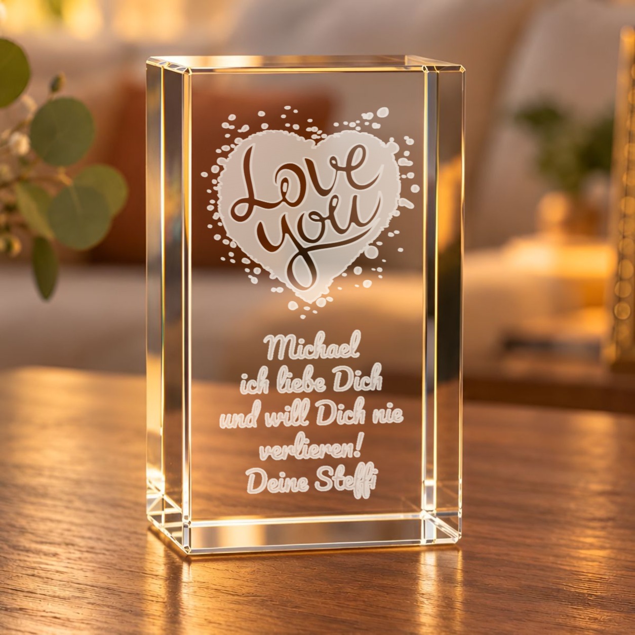 Glaskristall Love You mit Wunschtext: Glasquader mit gravuriertem Herz und Schriftzug „Love you“ auf einem Holztisch im Wohnzimmer