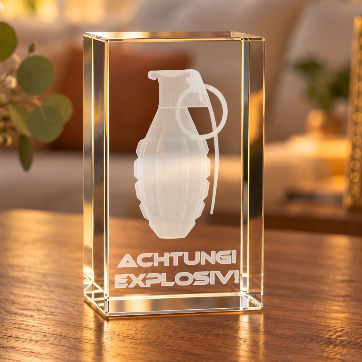 Glaskristall Handgranate mit 3D-Laserinnengravur und Schriftzug „Achtung! Explosiv!“ auf einem Holztisch im Wohnzimmer