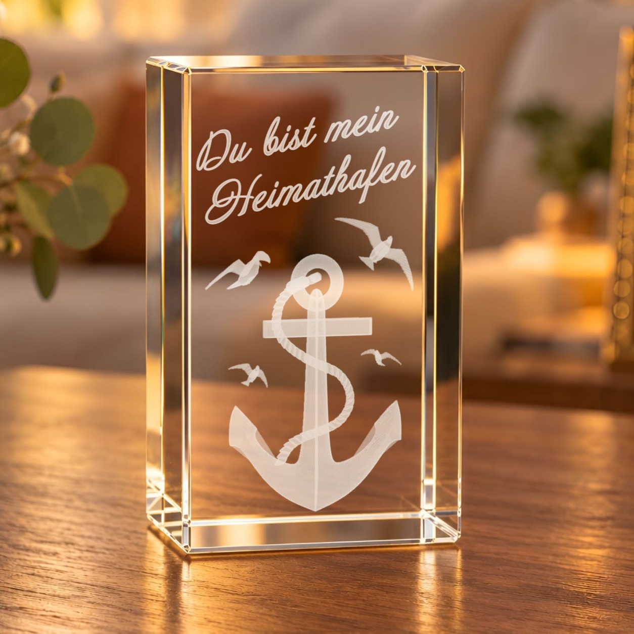 3D-Glaskristall Anker mit Möwen und Schriftzug „Du bist mein Heimathafen“ auf einem Holztisch im Wohnzimmer