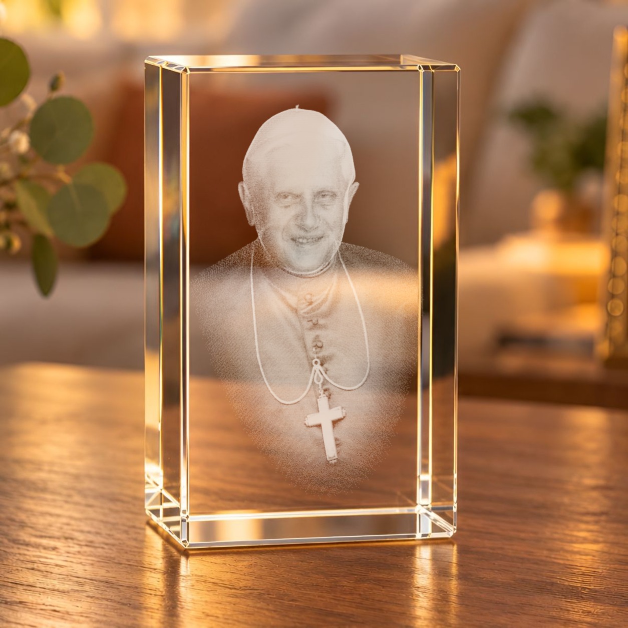 Glaskristall Papst Benedikt XVI. mit 3D-Laserinnengravur auf einem Holztisch im Wohnraum bei warmem Licht