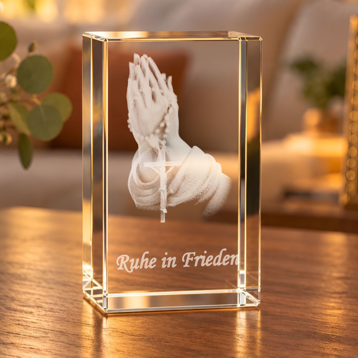 Glaskristall Betende Hände mit Rosenkranz und Schriftzug „Ruhe in Frieden“ auf einem Holztisch im Wohnzimmer